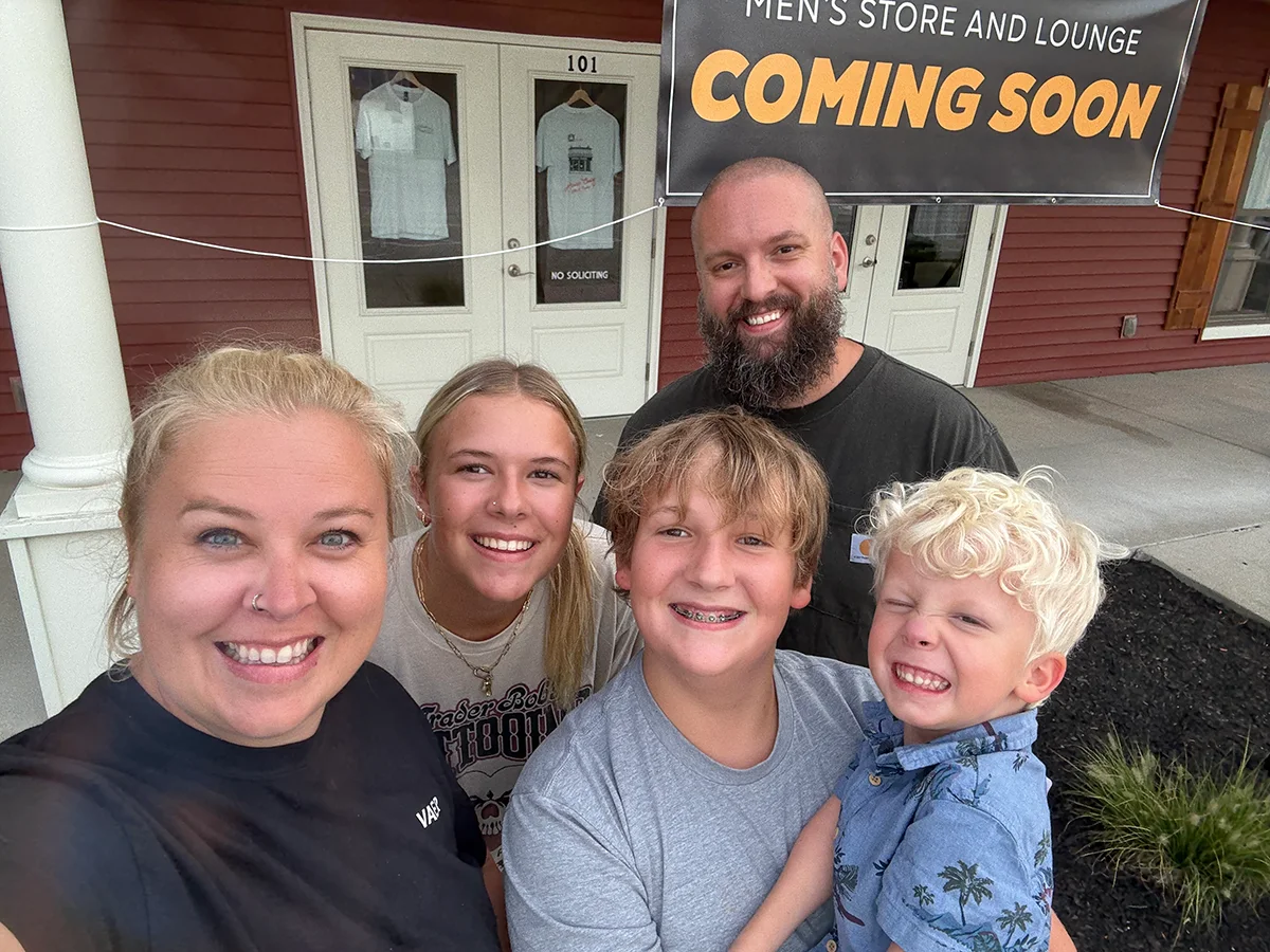The Raposo family stands beneath the coming-soon banner outside their future store.